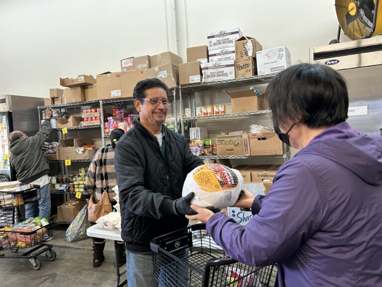 A volunteer hands a client a turkey.